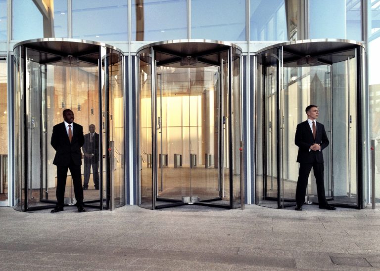 two security guards outside of an office skyscraper building